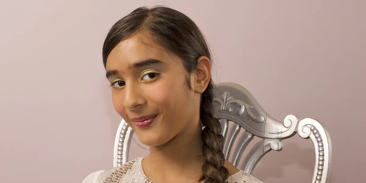 young girl with braided hair smiling during kids spa makeup session