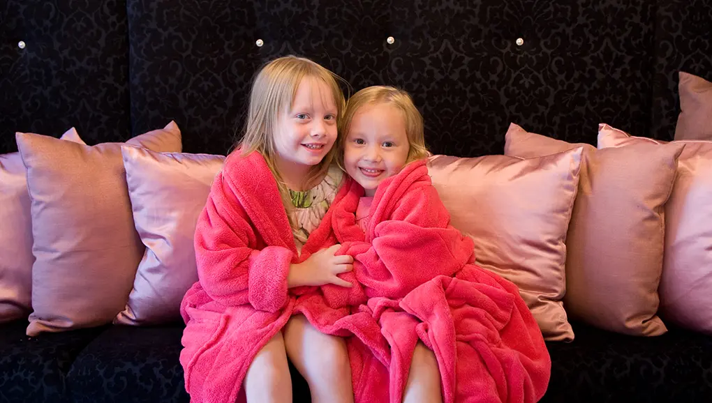 Two young girls wearing pink spa robes enjoying a fun pamper day at Feel Fabulous Kids Spa.